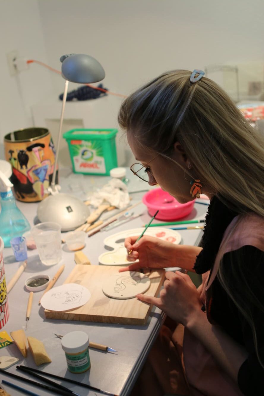 Eva décore une porcelaine au pinceau dans son atelier.